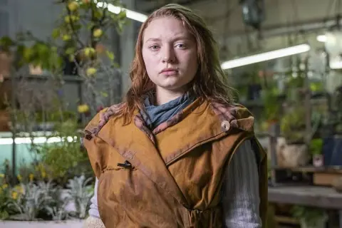 Mia Threapleton, con su mirada seria, posa en un invernadero lleno de plantas.