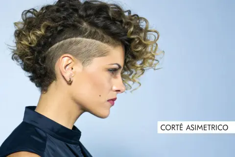 Mujer con pelo corto rizado y rapado asimétrico, luciendo un estilo audaz y moderno.