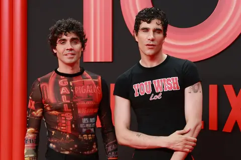 Javier Calvo y Javier Ambrossi posan sonrientes. Javier Calvo lleva una camiseta con estampado de luces de neón y Javier Ambrossi una camiseta negra con el lema "You Wish Lol".