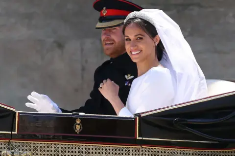 Meghan Markle y el Príncipe Harry sonríen en su carruaje nupcial. La novia luce un velo y tiara deslumbrantes en su boda.