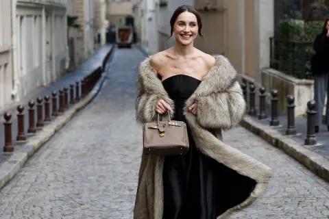 Elegante mujer con abrigo de pelo y bolso, lista para una boda en invierno.