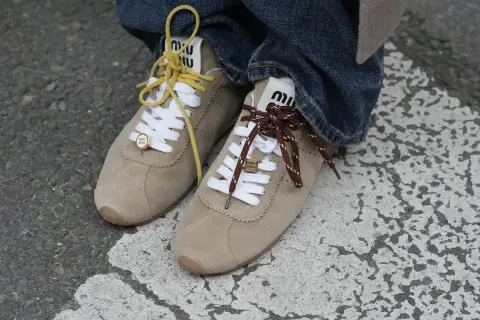 Zapatillas Miu Miu de ante beige, con cordones amarillos y marrones, un toque de zapatillas tendencia.
