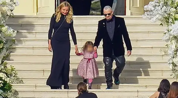 Cameron Diaz camina de la mano con su hija y su esposo por unas escaleras adornadas con flores.