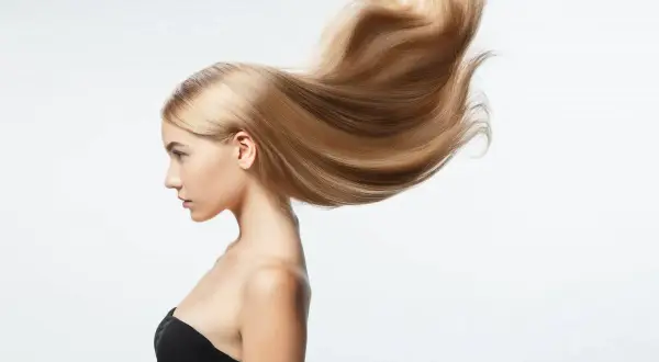 Perfil de mujer con pelo largo rubio y sedoso que se mueve con el viento.