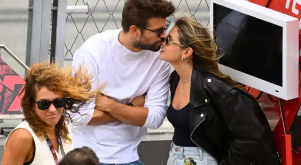 Piqué y Clara Chía se besan apasionadamente, ajenos a la mujer con pelo rizado y gafas de sol que les mira de reojo.