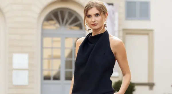 Mujer con un elegante vestido de negro, luciendo unos llamativos pendientes dorados.