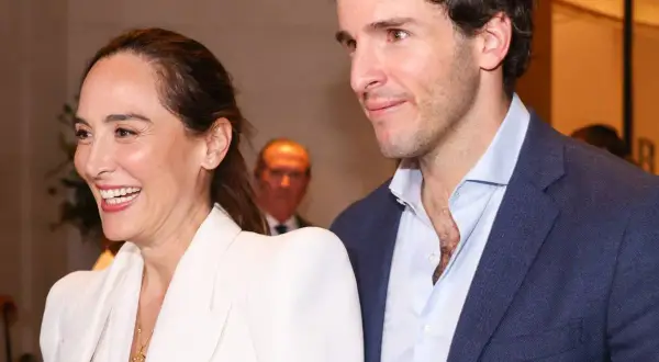 Tamara Falcó e Iñigo Onieva sonríen juntos, ella con un elegante traje blanco y él con chaqueta azul.