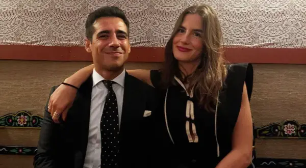 Pareja sonriente, él con traje y corbata de puntos, ella con vestido negro. Blanca Llandres, un momento íntimo capturado.