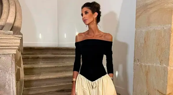 Inés Domecq posa con un elegante vestido negro de escote Bardot y falda voluminosa color crema, luciendo joyas doradas.