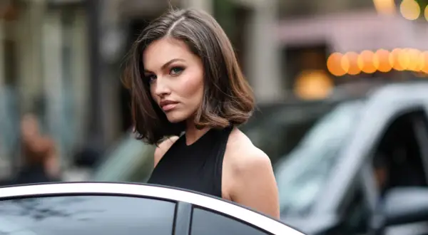 Mujer con corte bob asimétrico, ideal para cortes de pelo para cara redonda, luciendo elegante junto a un coche.