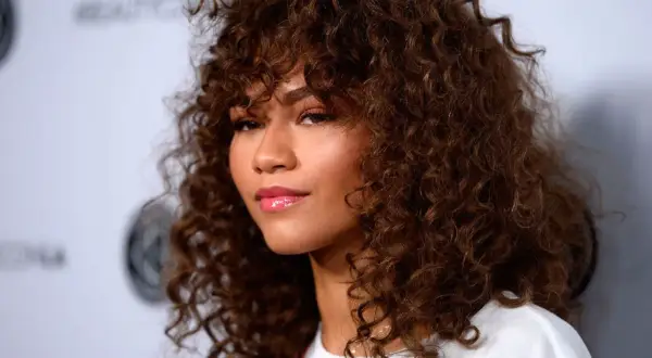Mujer con pelo muy corto rizado natural, castaño y voluminoso, con flequillo.