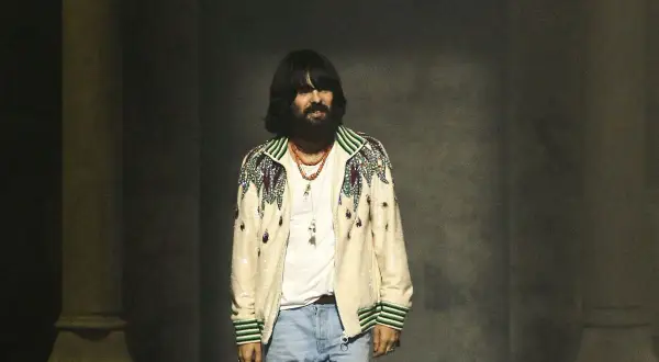 Alessandro Michele, con su icónico estilo, luce una chaqueta bordada y jeans.