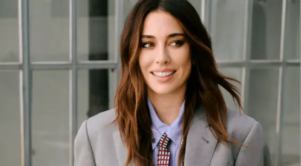 Blanca Suárez, con su melena castaña al viento, sonríe con confianza luciendo un traje gris y corbata.
