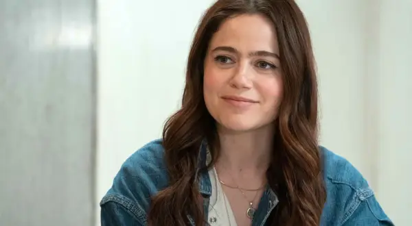 Molly Gordon, con su cabello castaño suelto y una chaqueta vaquera, sonríe con dulzura.