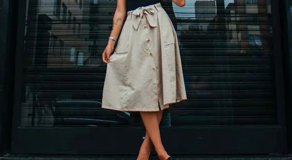 Mujer con falda beige abotonada y lazo, mostrando diferentes tipos de faldas para un look casual chic.