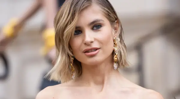 Mujer con un elegante corte bob a capas, aretes dorados y maquillaje sutil.