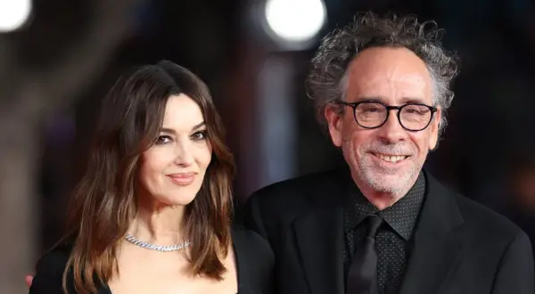 Monica Bellucci y Tim Burton, una pareja que parece sacada de una película de fantasía gótica, posan juntos con elegancia.