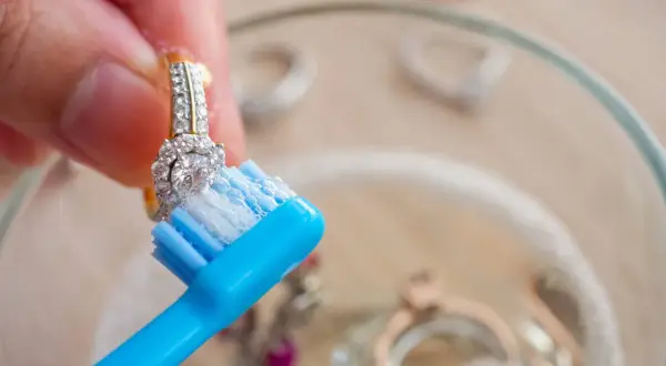 Limpia joyas con un cepillo de dientes azul y jabón.