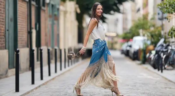 Mujer con falda larga de flecos y top blanco, lista para la feria de abril sin vestido.