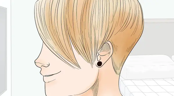 Perfil de persona con cabello rubio, mostrando la transición de pelo corto a largo. Se ve un pendiente negro.