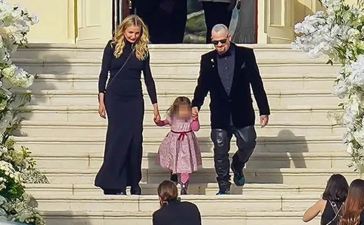 Cameron Diaz camina de la mano con su hija y su esposo por unas escaleras adornadas con flores.