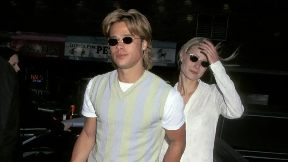 Brad Pitt joven con gafas de sol y un suéter a rayas, junto a una mujer rubia.