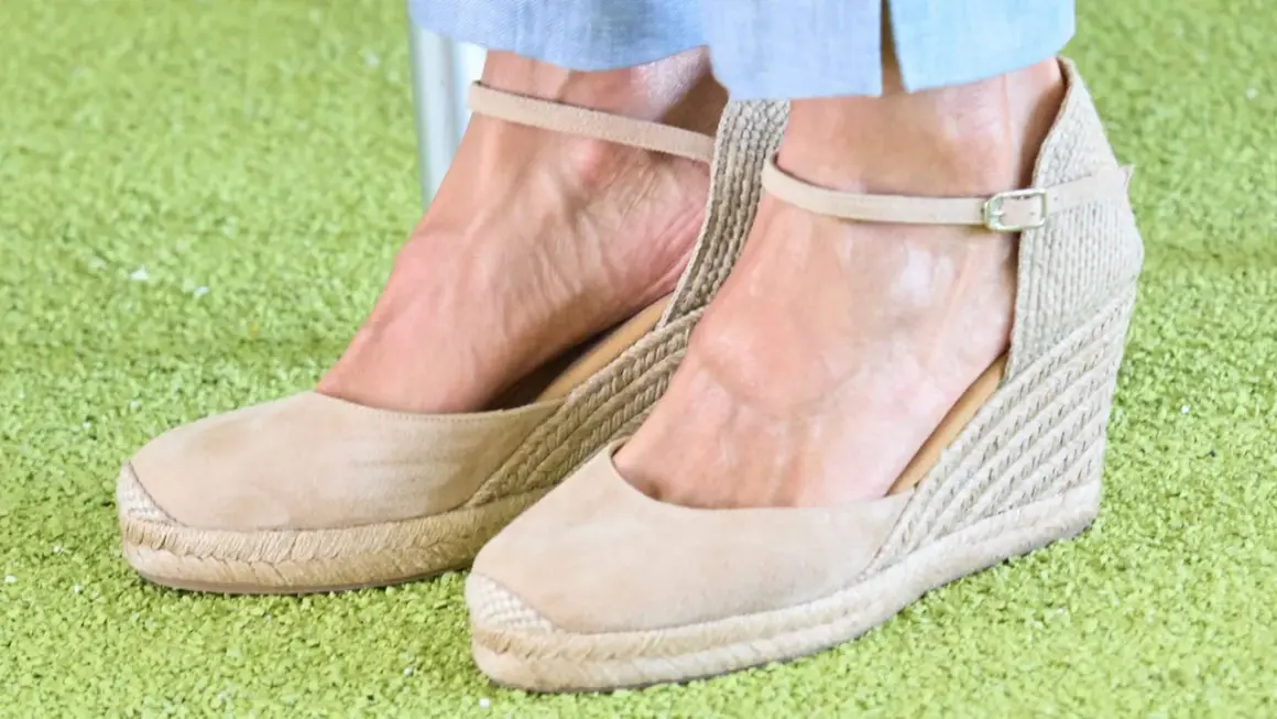 Alpargatas de cuña color camel, con tiras al tobillo, similares a las que usa la reina Letizia, sobre una alfombra verde.
