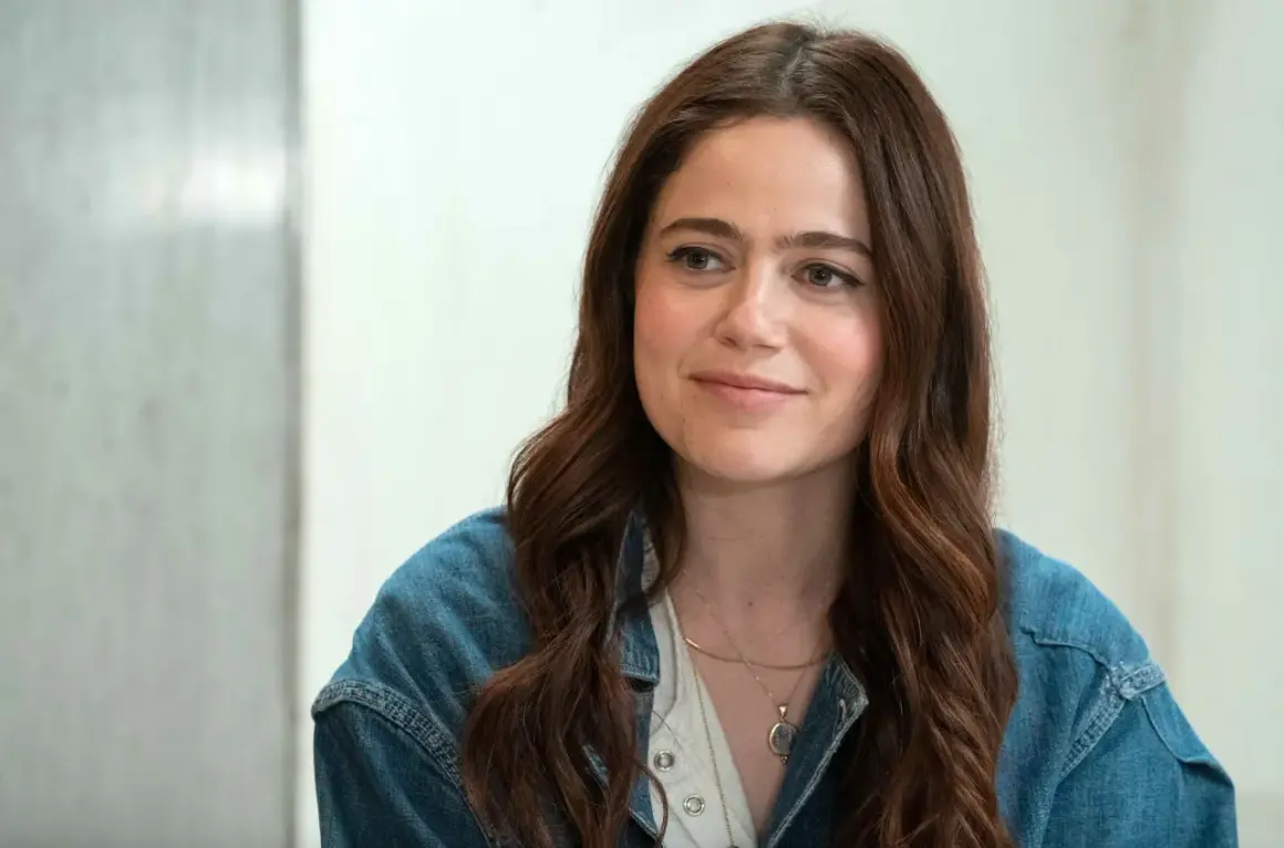 Molly Gordon, con su cabello castaño suelto y una chaqueta vaquera, sonríe con dulzura.