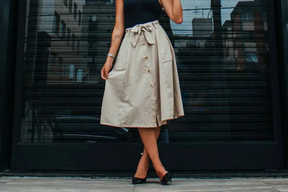 Mujer con falda beige abotonada y lazo, mostrando diferentes tipos de faldas para un look casual chic.