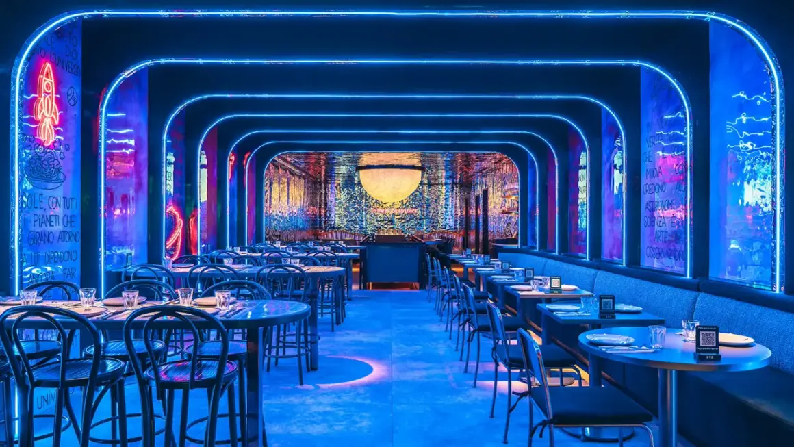 Un restaurante futurista con luces de neón azules y arte mural. Mesas puestas para cenar, quizás para disfrutar de una beata pasta bajo las estrellas.