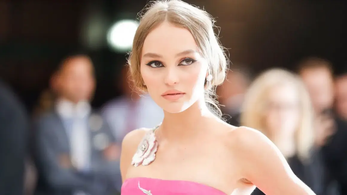 Lily-Rose Depp, con un vestido rosa y maquillaje dramático, posa con elegancia.