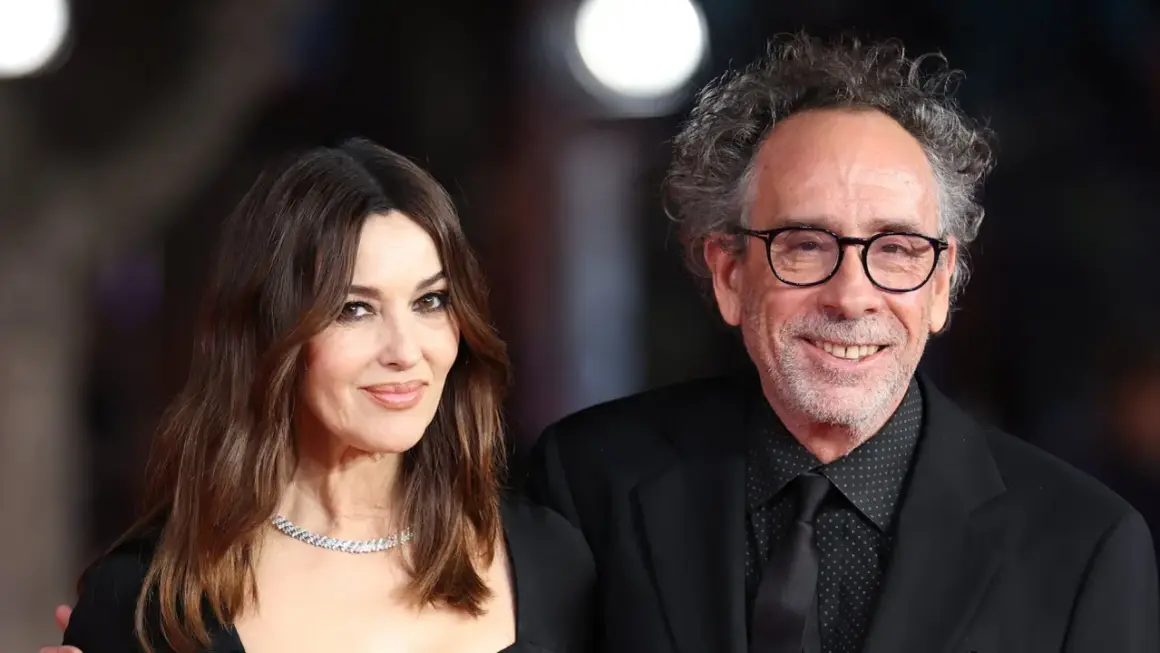 Monica Bellucci y Tim Burton, una pareja que parece sacada de una película de fantasía gótica, posan juntos con elegancia.