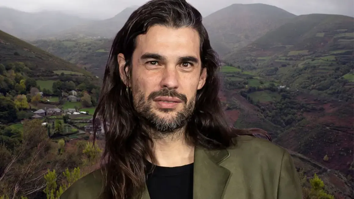 Oliver Laxe, director, posa con una barba cuidada y pelo largo, frente a un paisaje montañoso de Galicia.