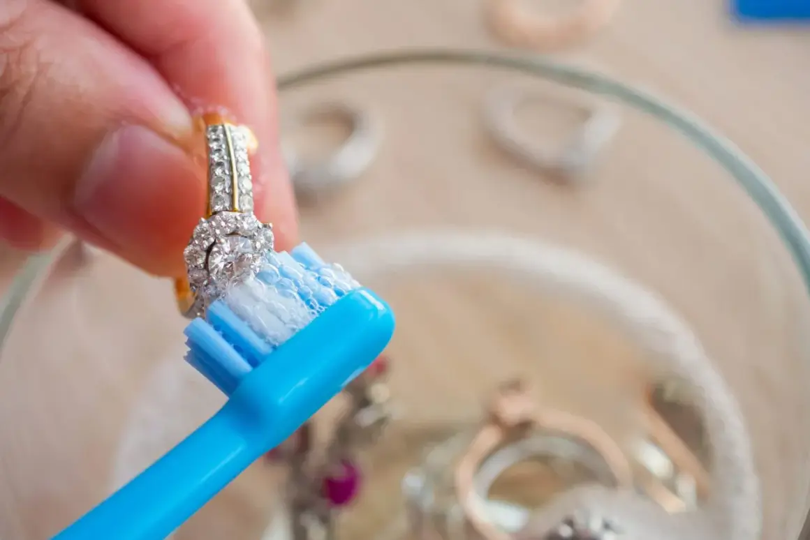 Limpia joyas con un cepillo de dientes azul y jabón.