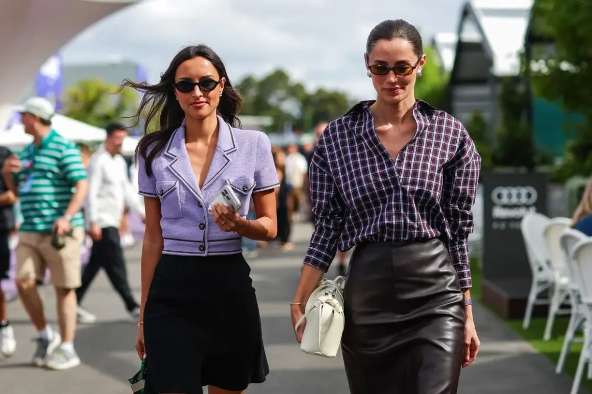 Rebecca Donaldson y su amiga pasean con estilo. Una lleva un blazer lila y falda negra, la otra, camisa a cuadros y falda de cuero.