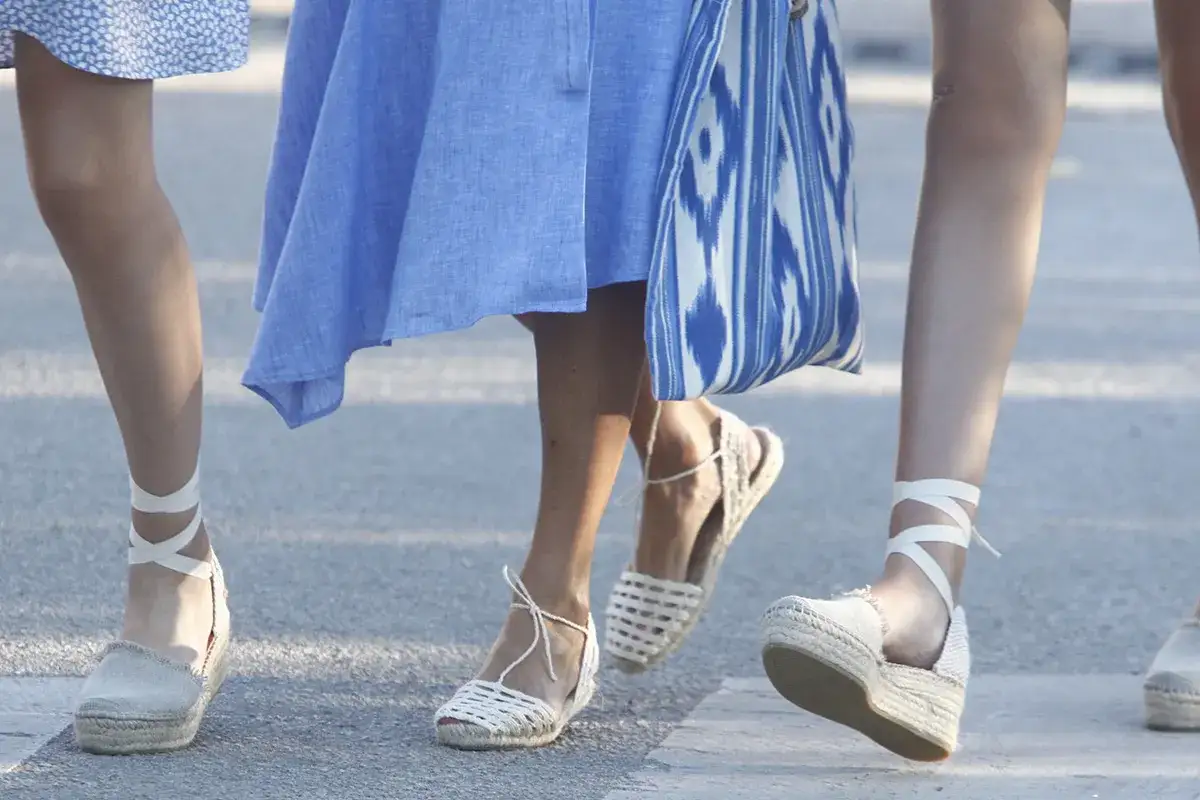 Pies con alpargatas reina Letizia, unas de cuña con lazada y otras planas de esparto, paseando con un vestido azul.