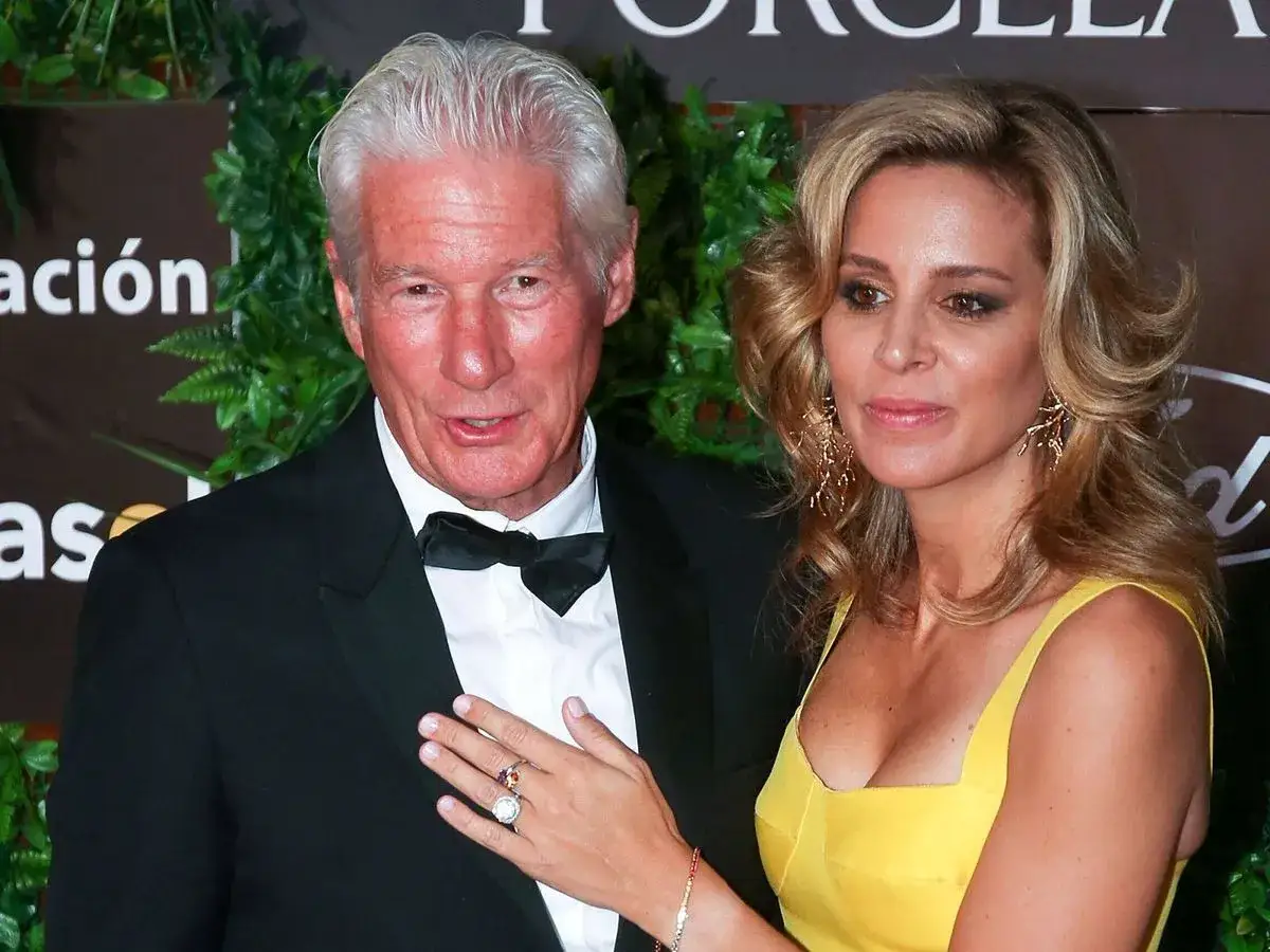 Richard Gere y su mujer, Alejandra Silva, posan sonrientes. Ella luce un vestido amarillo y él un esmoquin negro.