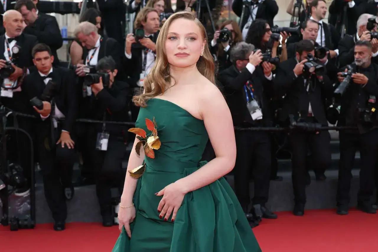 Mia Threapleton desfila en la alfombra roja con un vestido verde esmeralda, rodeada de fotógrafos.
