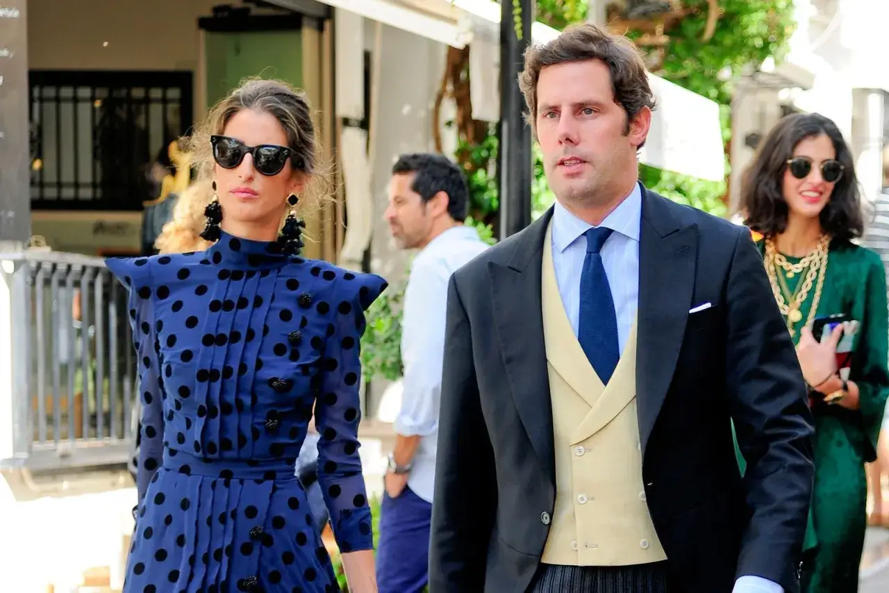 Javier Martínez de Irujo, elegante con traje, camina junto a una mujer con vestido de lunares.