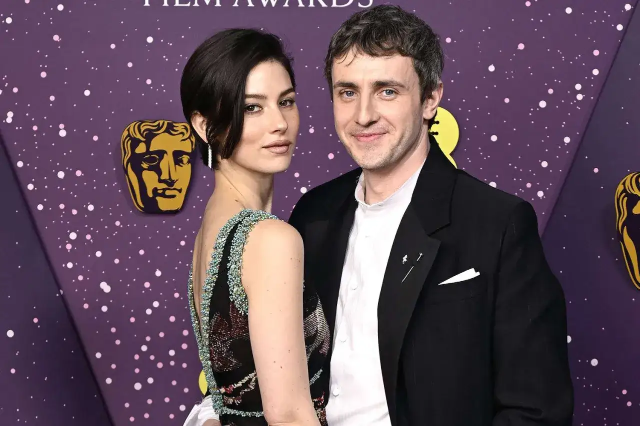 Paul Mescal y su pareja posan sonrientes ante un fondo morado con estrellas y el logo de BAFTA.