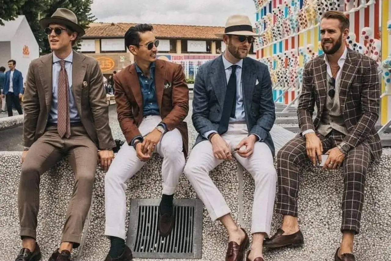 Cuatro hombres con trajes elegantes y sombreros, perfectos para ir a la feria de d&iacute;a.