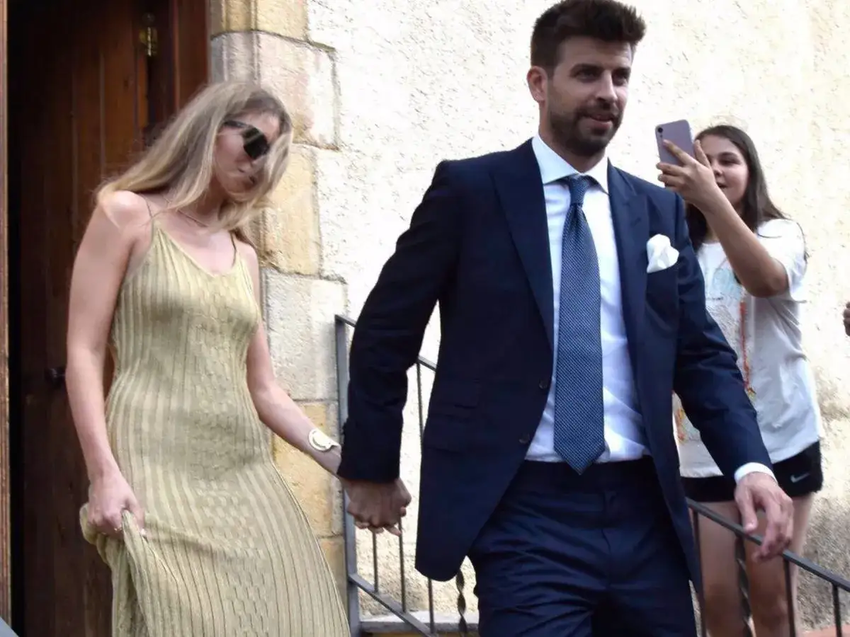 Piqu&eacute; y Clara Ch&iacute;a, tomados de la mano, salen de un evento. Una joven les toma una foto con su m&oacute;vil.