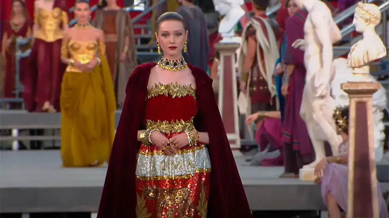 Desfile inspirado en la antigua Roma, con modelos luciendo trajes dorados y rojos. Maria Grazia Chiuri crea un espect&aacute;culo majestuoso.