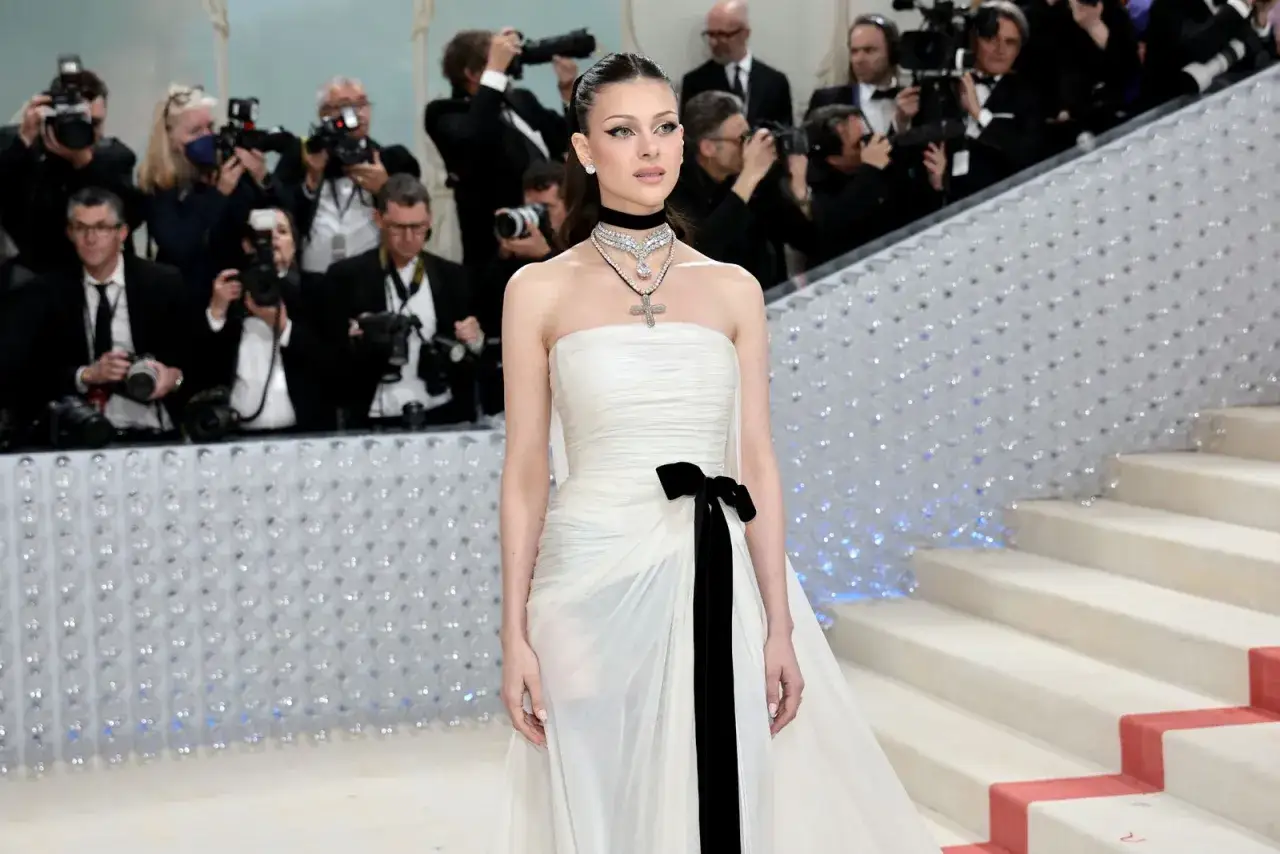 Nicola Peltz, deslumbrante con un vestido blanco y negro, posa ante una multitud de fotógrafos.