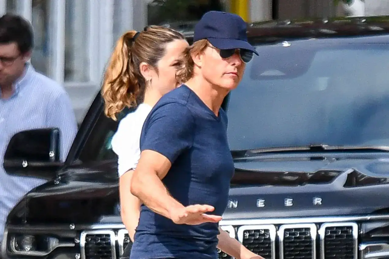 Tom Cruise y Ana de Armas, con gorra y gafas de sol, caminan junto a un coche negro.