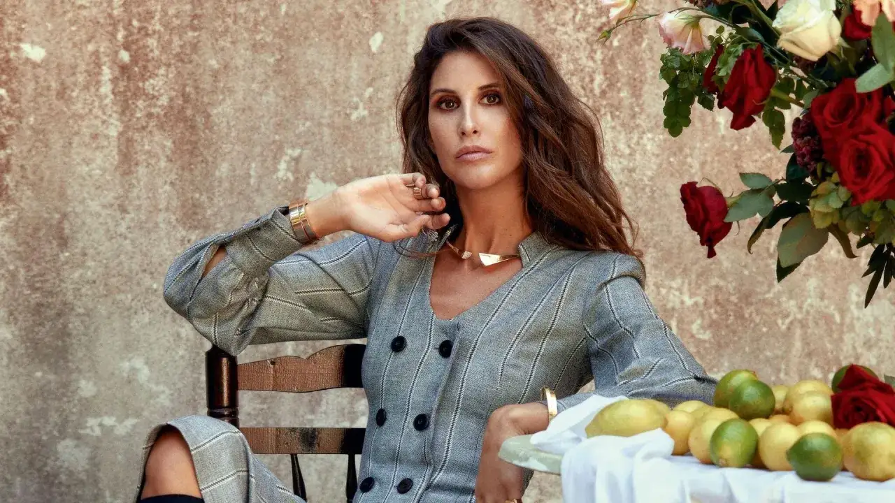 In&eacute;s Domecq, elegante con traje de raya diplom&aacute;tica, posa con un collar dorado y un ramo de rosas rojas.