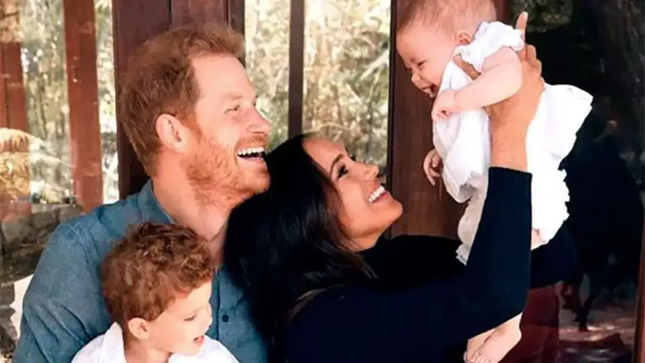 Harry y Meghan sonríen mientras sostienen a su bebé, con su hijo mayor cerca. Los hijos de Harry y Meghan irradian felicidad.