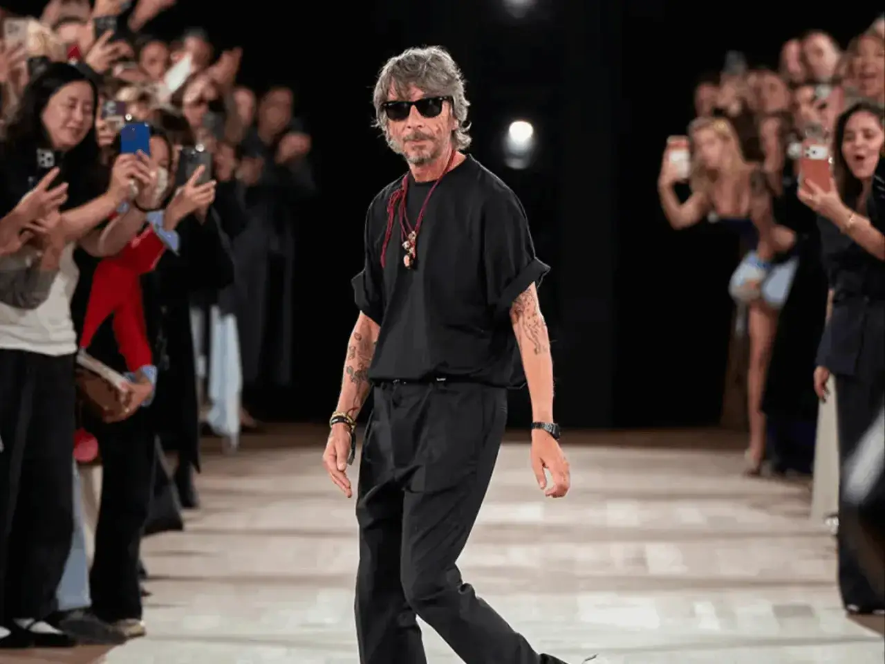 Pierpaolo Piccioli, con gafas de sol y look total black, camina por la pasarela mientras el p&uacute;blico graba con sus m&oacute;viles.