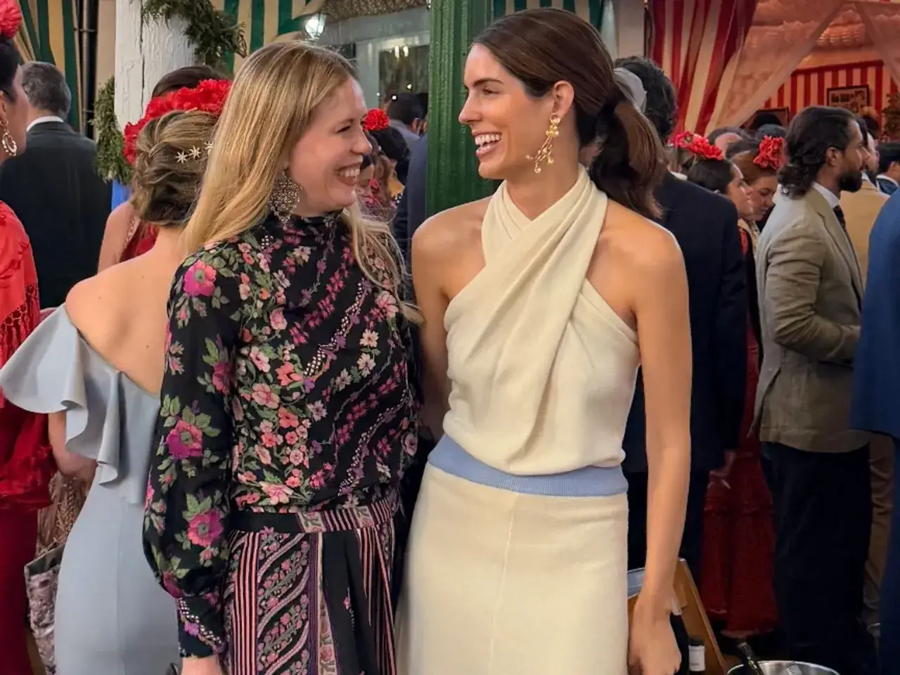 Sofía Palazuelo sonríe con un vestido crema, junto a una amiga con estampado floral.