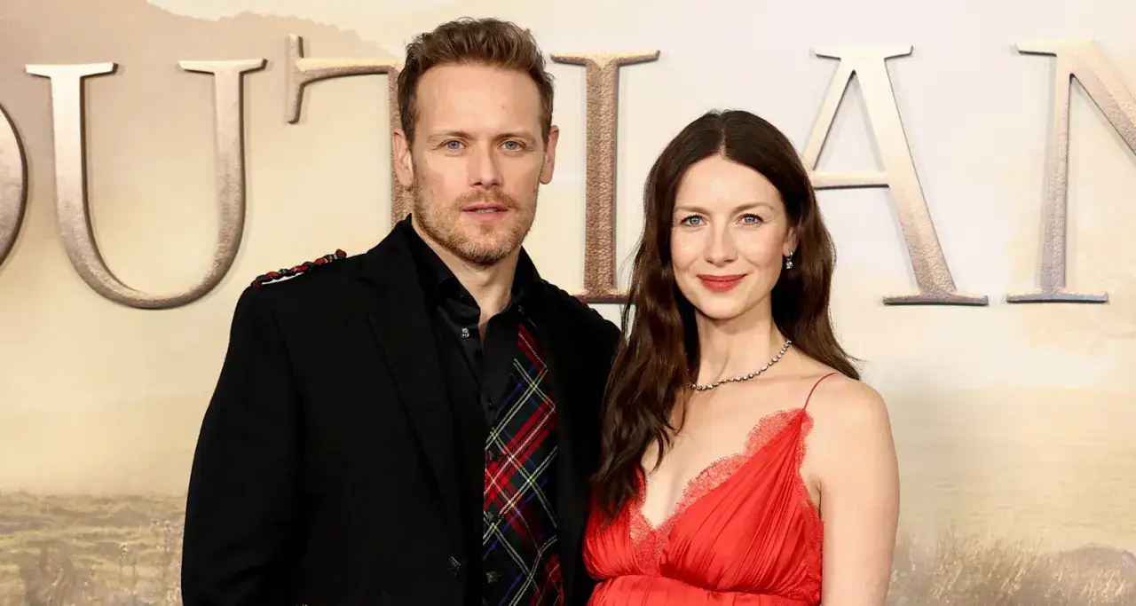 Sam Heughan y su pareja, Caitriona Balfe, posan juntos en un evento. &Eacute;l lleva un traje negro con detalles escoceses y ella un vestido rojo.